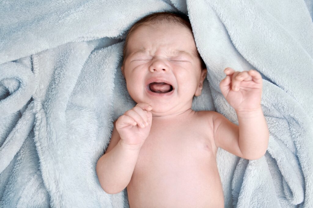 Crying,Newborn,Baby,Boy,Lying,On,Soft,Plaid,At,Home